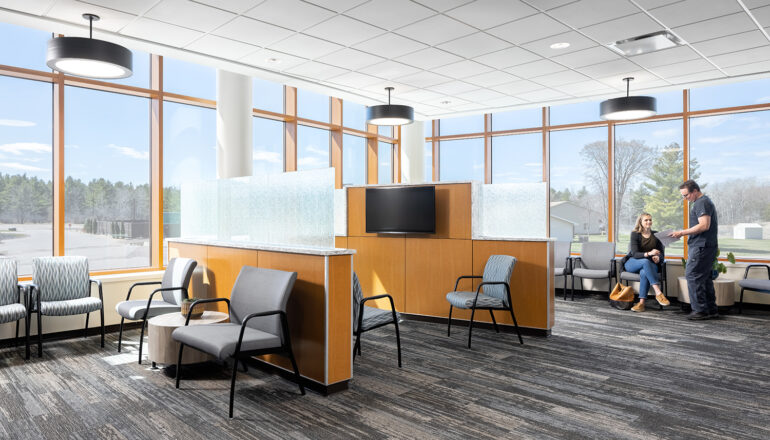 People talk in the waiting room outside of the MMC Ashland Surgery Center. Low privacy dividers and wrap-around floor to ceiling windows keep patients and visitors comfortable