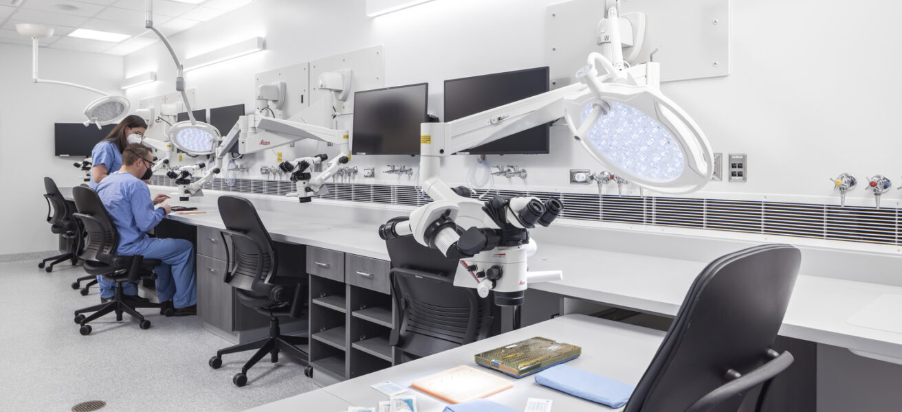 People use a microscope in the Mayo Clinic simulation space.