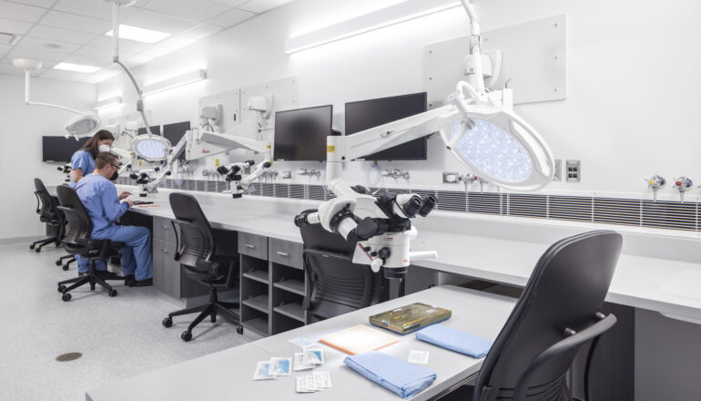 People use a microscope in the Mayo Clinic simulation space.