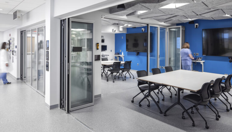 People in two debriefing rooms with sliding glass panels in the Mayo Clinic simulation center.