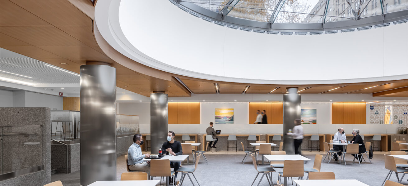 People eat together in the Siebens Cafeteria. An enormous glass skylight brings the city into the space