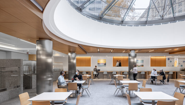 People eat together in the Siebens Cafeteria. An enormous glass skylight brings the city into the space