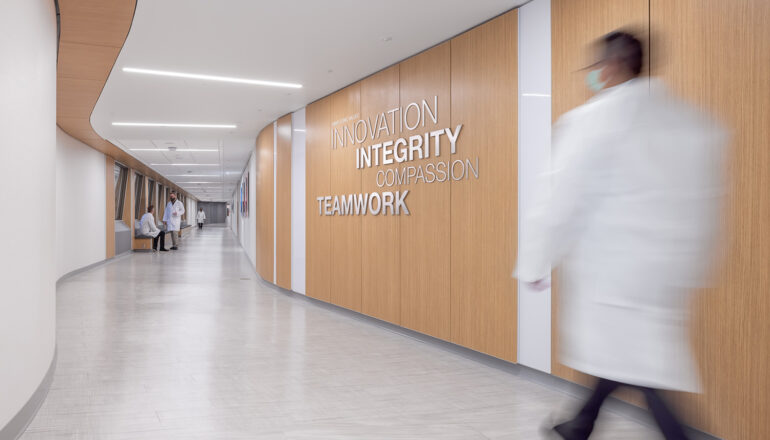 Doctors and staff in white coats walk down a staff corridor. Mayo Clinic's values are boldly stated on the wall: Innovation, Integrity, Compassion, Teamwork