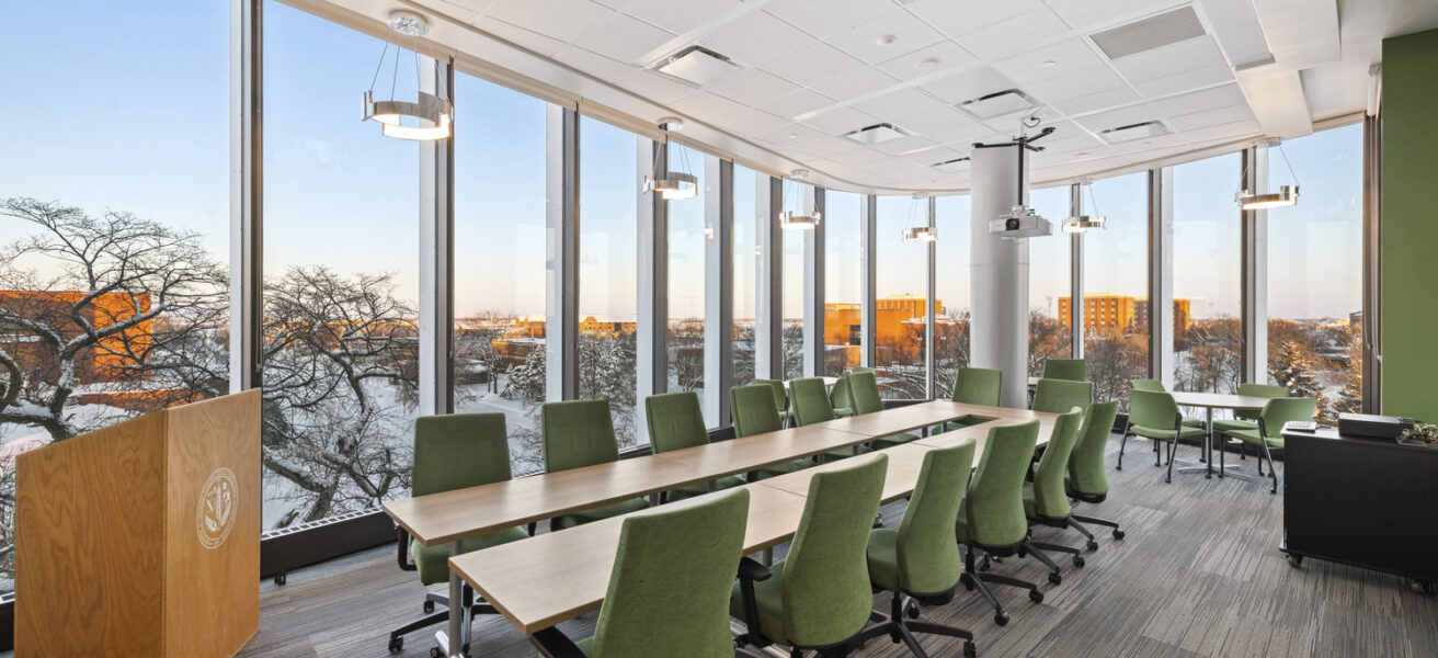 A conference room with green chairs and views of campus.