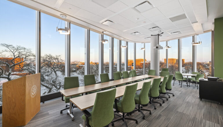 A conference room with green chairs and views of campus.