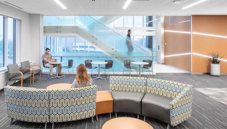 A waiting area with a variety of seating options and access to abundant daylight from the glass-enclosed stairwell.