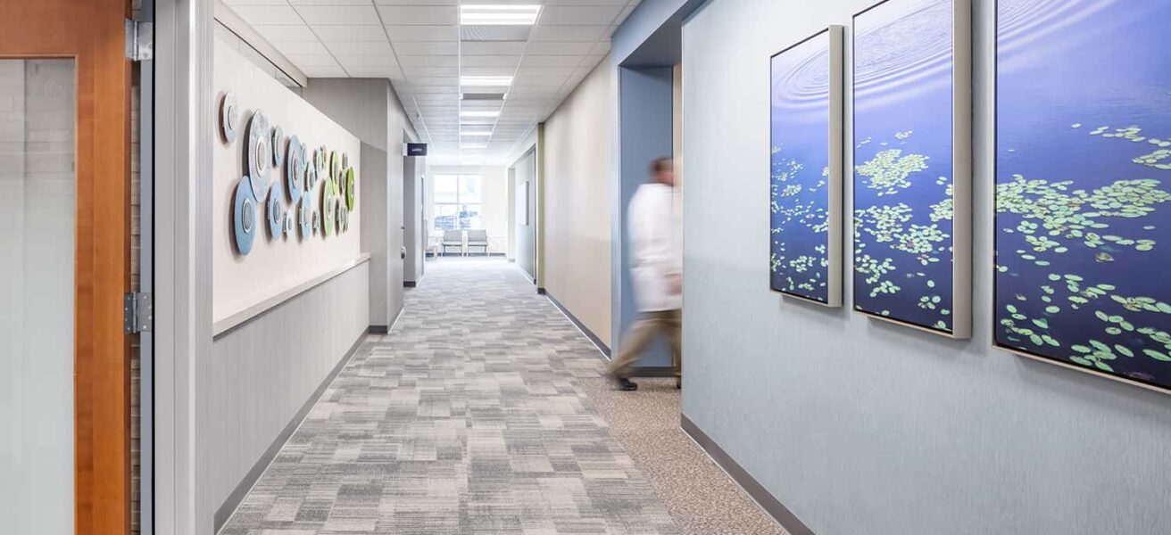 A doctor utilizes an interior corridor with nature-inspired artwork.