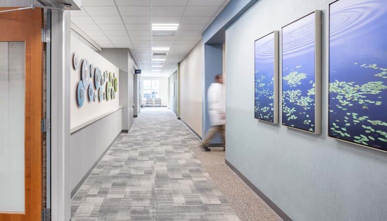 A doctor utilizes an interior corridor with nature-inspired artwork.