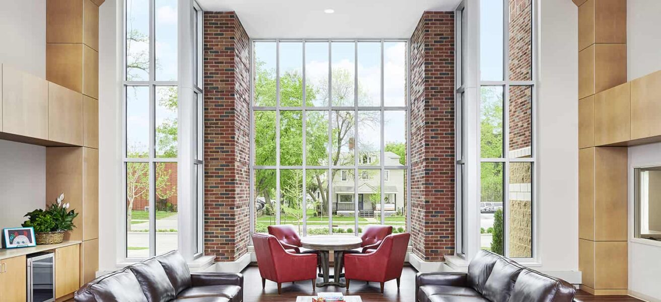 Shared open living space with floor to ceiling windows that let in daylight and views to the neighborhood.