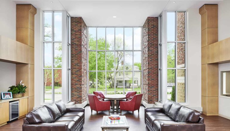 Shared open living space with floor to ceiling windows that let in daylight and views to the neighborhood.