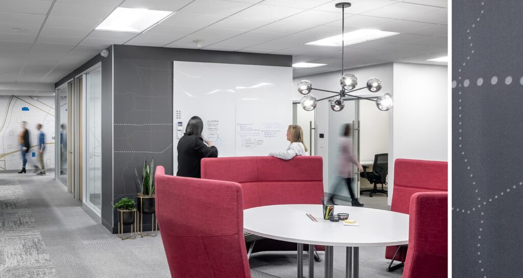 A touchdown station with brightly colored furniture and a whiteboard for collaboration.