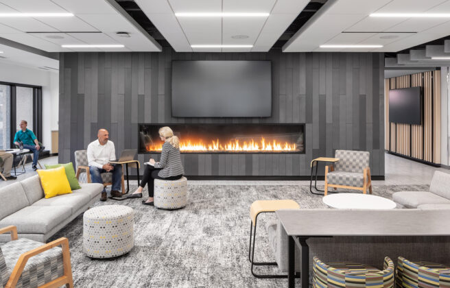 People collaborate and work in the Securian lounge with a fireplace