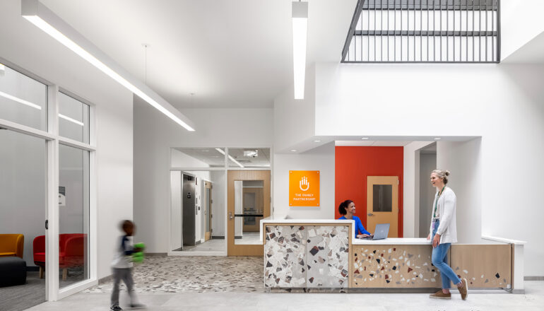 People in The Family Partnership's lobby and reception area with double-height ceiling.