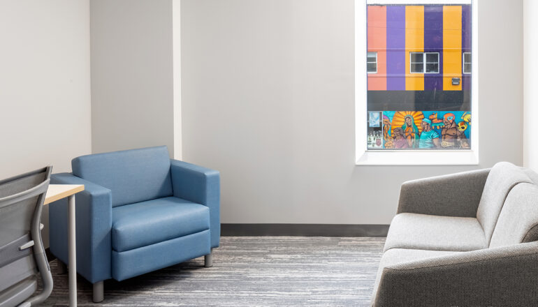 An example of a therapy room with comfortable furniture and views to the neighborhood's artwork.