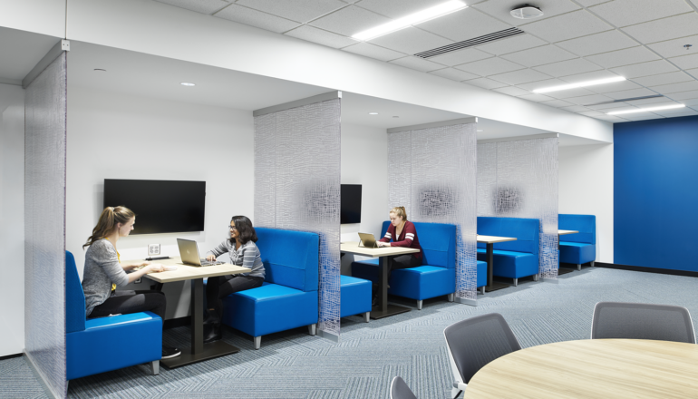 Students work in blue benchstyle seating nooks with monitors to share their biological sciences research