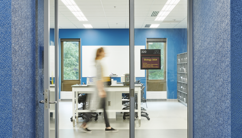 A student walks past a brightly lit entry to the Active Learning Lab