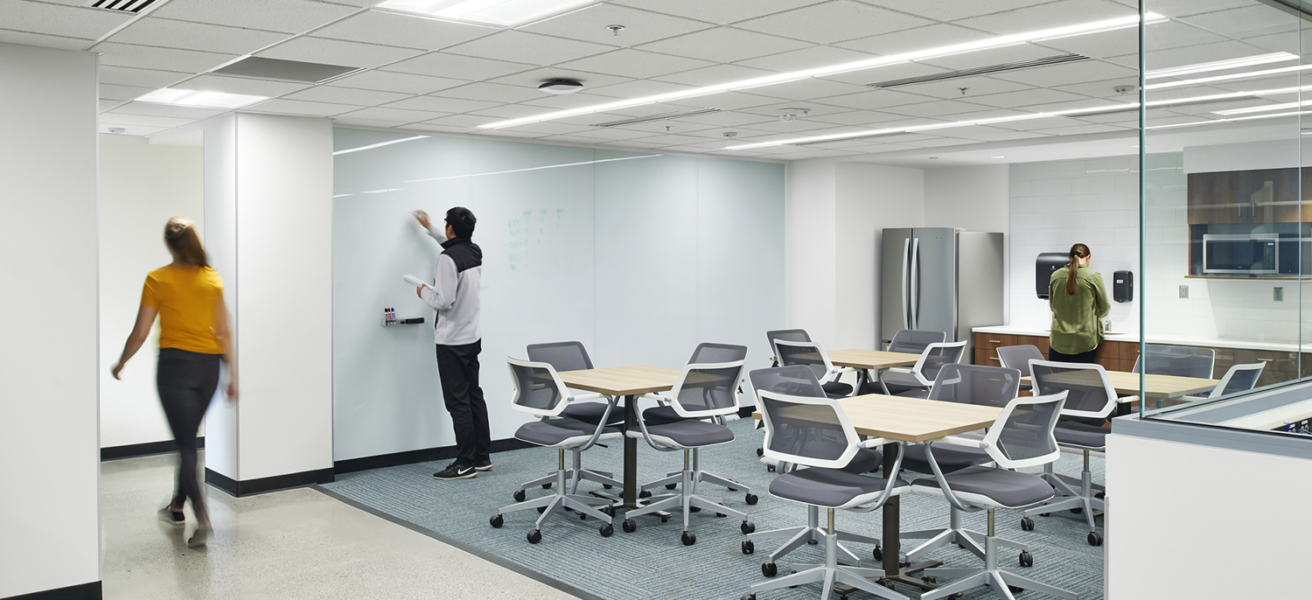 Students work in an open student commons with flexible seating options and a shared kitchenette