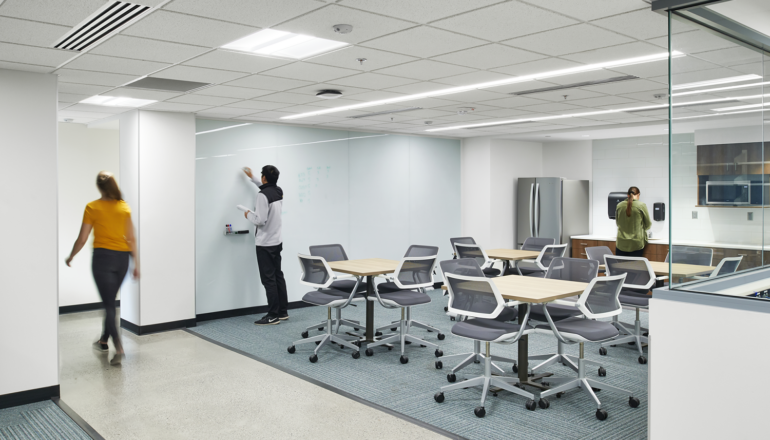 Students work in an open student commons with flexible seating options and a shared kitchenette