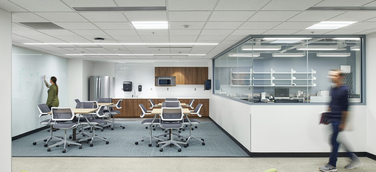 Students work in an open student commons with flexible seating options and a shared kitchenette