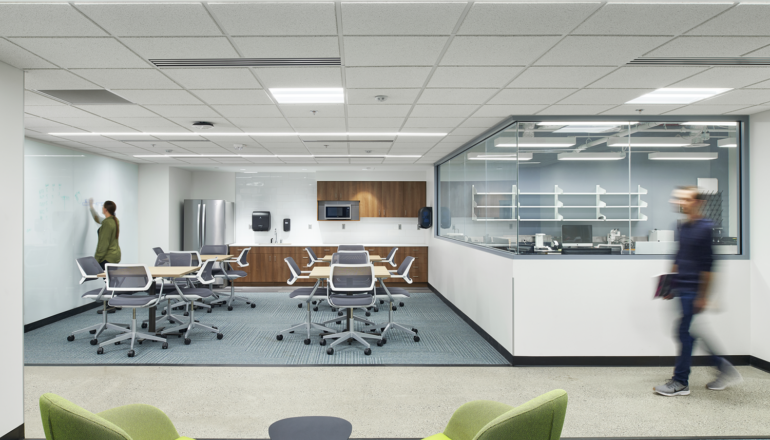 Students work in an open student commons with flexible seating options and a shared kitchenette