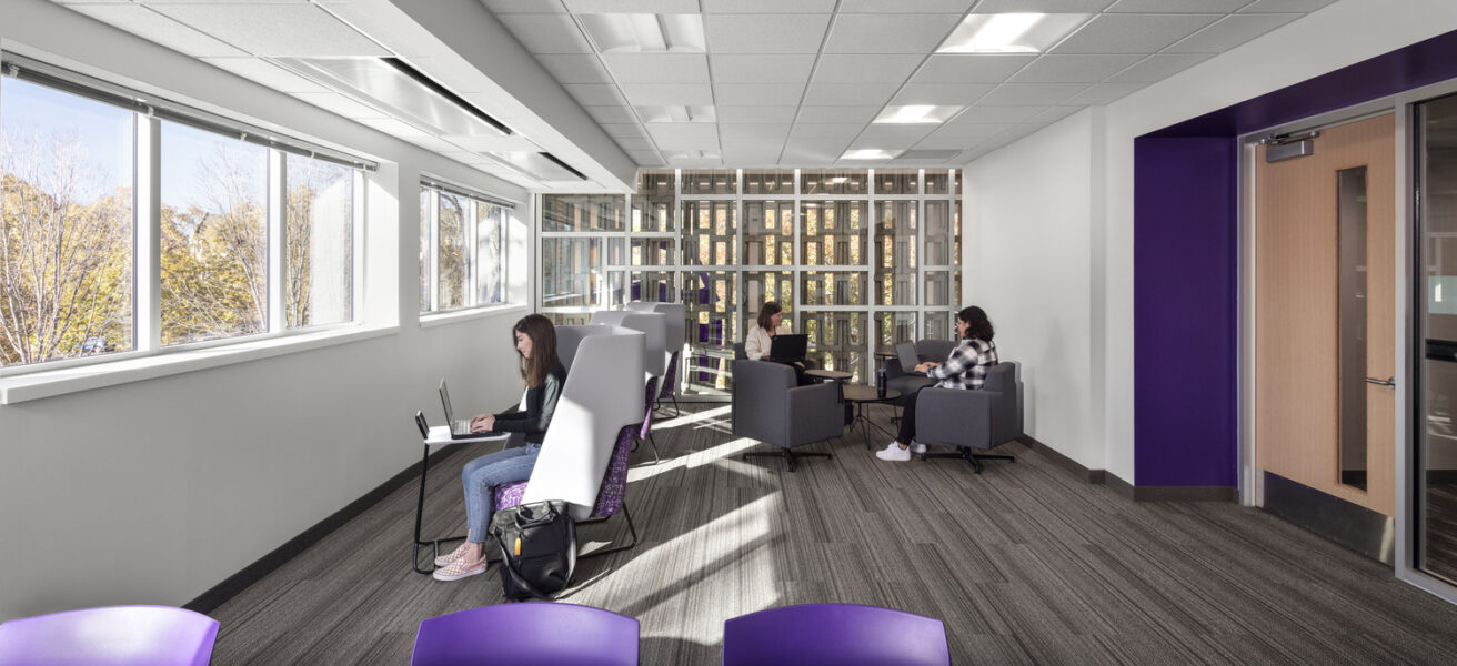 Students collaborate in a classroom with views into the renovated stairwell and to the outdoors.