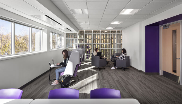 Students collaborate in a classroom with views into the renovated stairwell and to the outdoors.