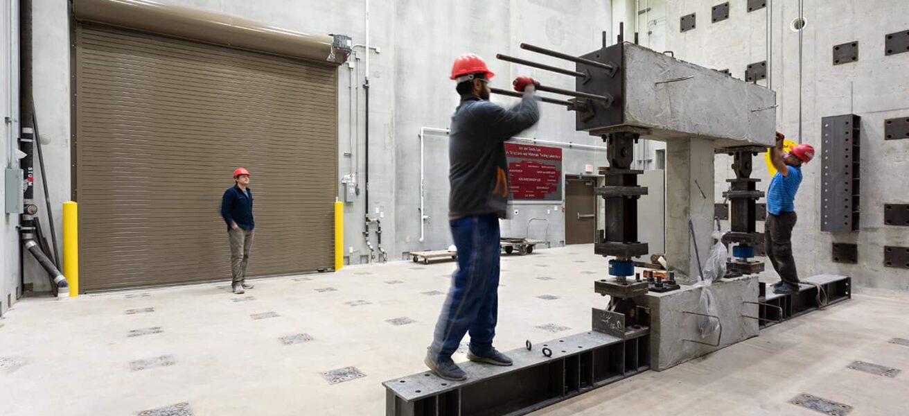 Engineering students adjust testing equipment in the structures lab.