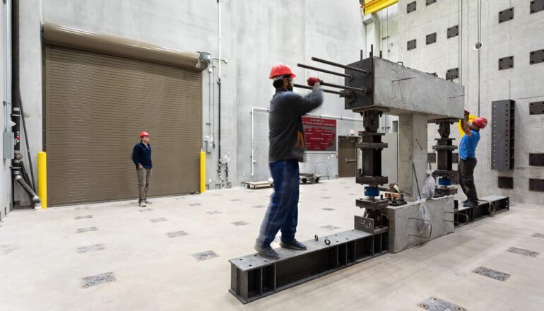 Engineering students adjust testing equipment in the structures lab.