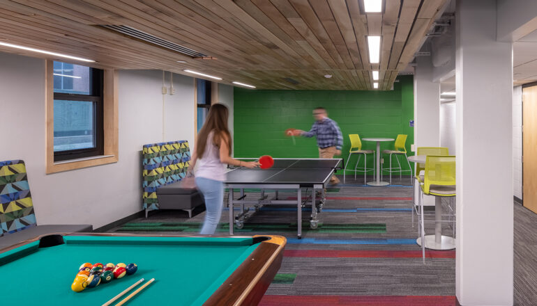 Students play ping pong next to a pool table in the North Hall game room