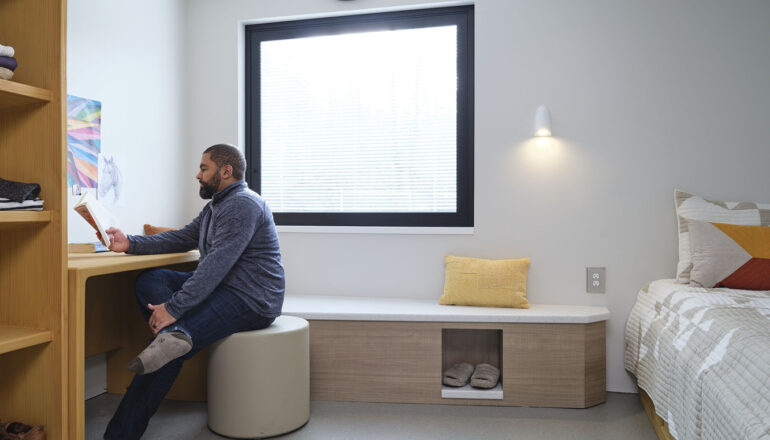 A person sits at the desk in one of the Maple Lane patient bedrooms.