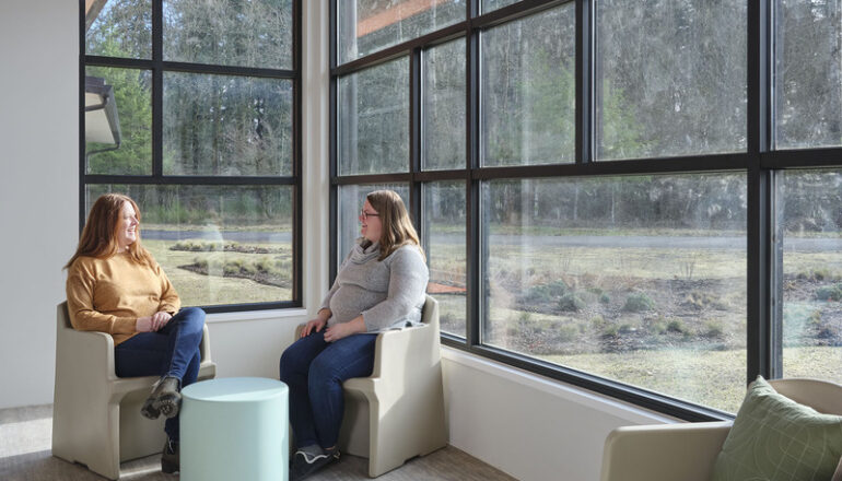 Two people sit in a sunny spot in the Maple Lane facility.