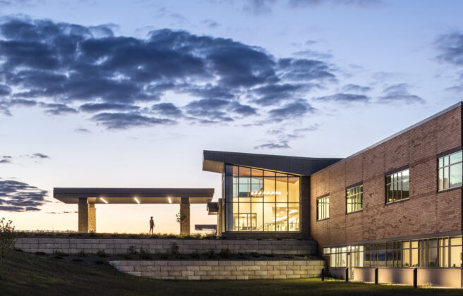 A person walks into the front entry of the JCRHC at dusk, as seen from a distance.